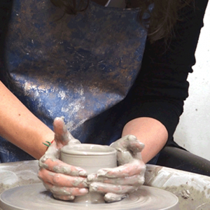 An Image of two hands working on a piece of clay on the pottery wheel